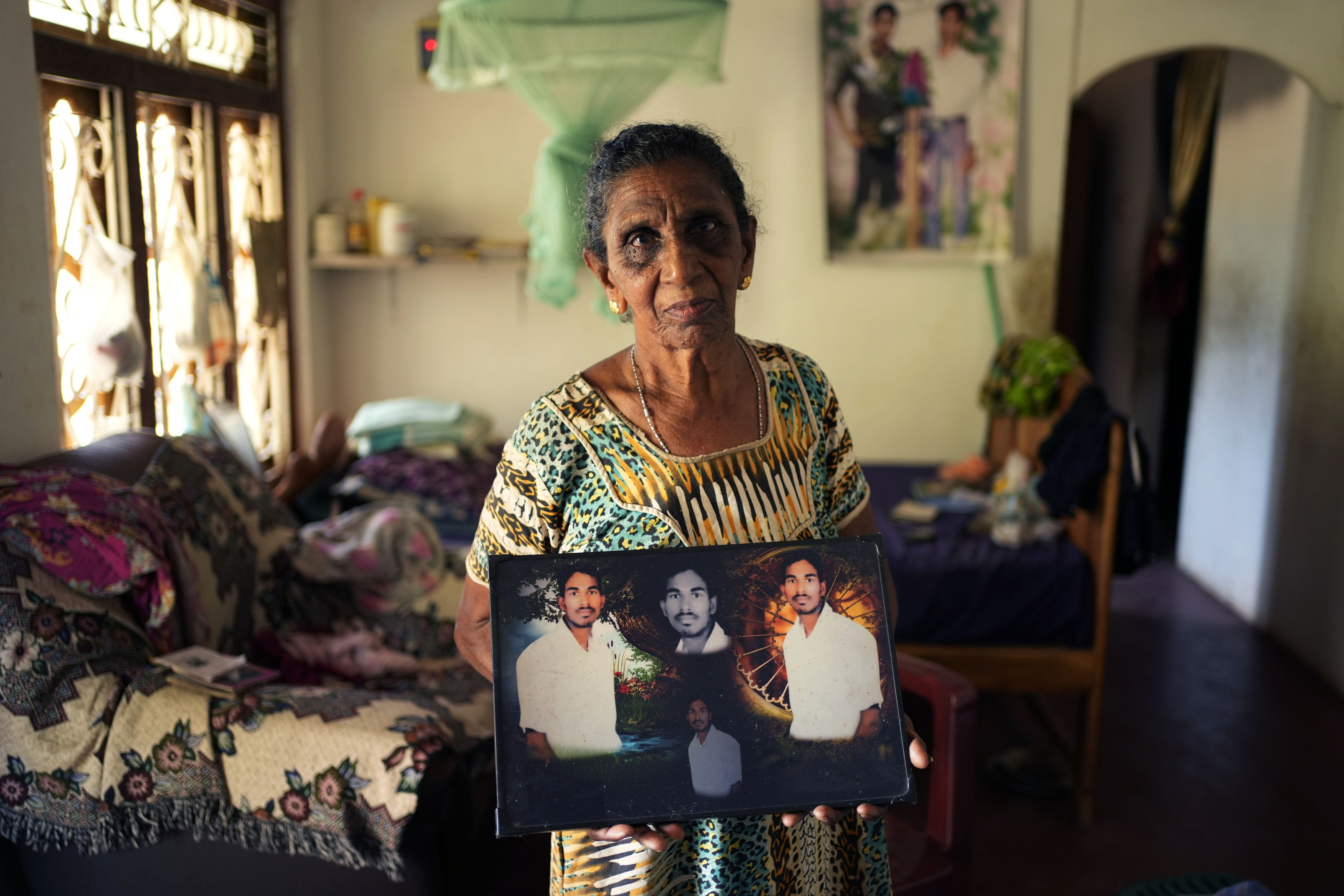 Soosai Victoria shows photographs of her missing son at her home in Mullaitivu, Sri Lanka, May 7, 2024.